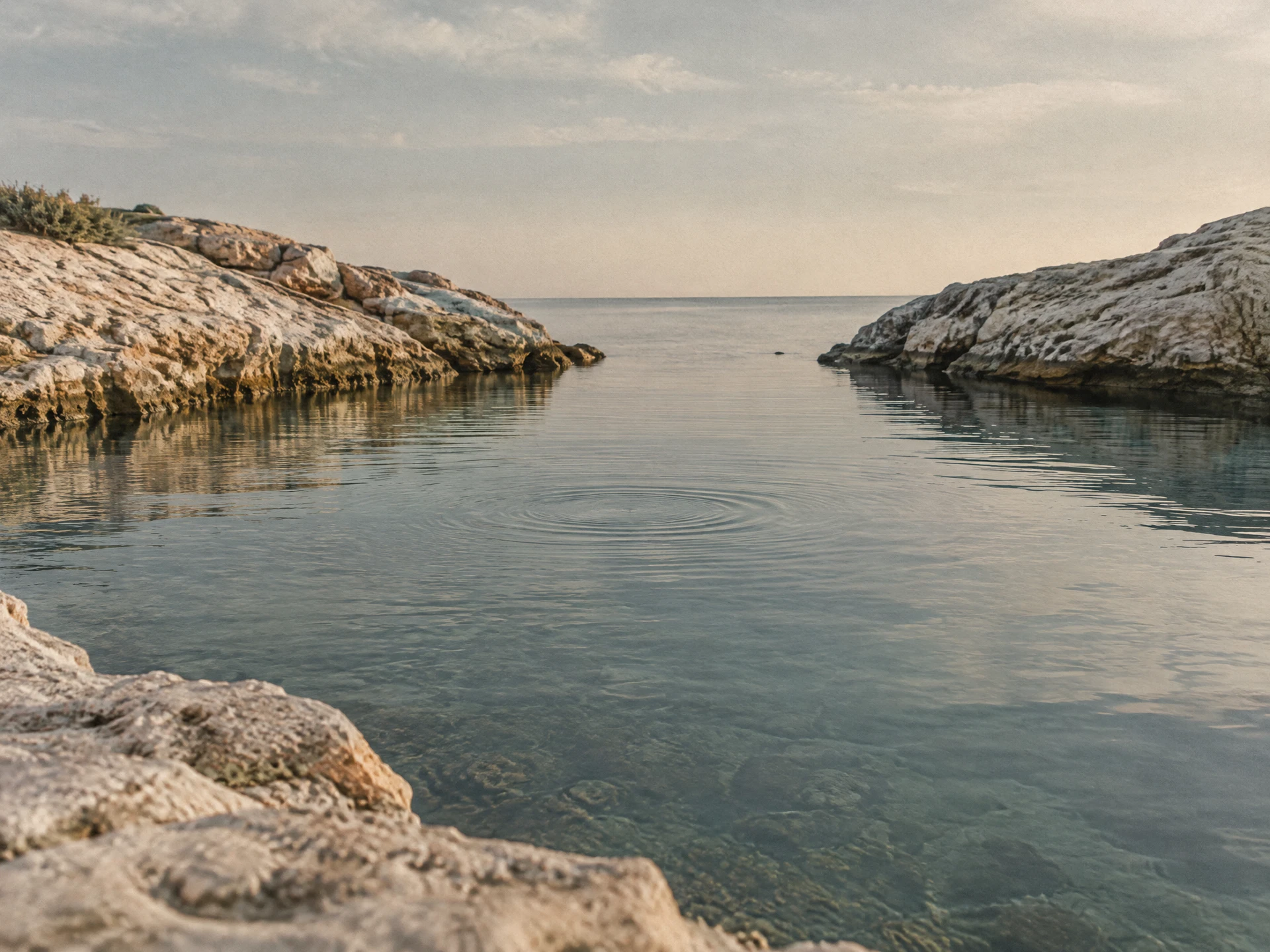 Still gray-blue water held between pale limestone edges under diffuse early morning light.